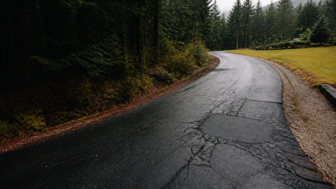 Weathered asphalt driveway with interconnected cracking on a Maple Ridge acreage